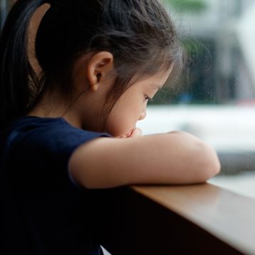 Niña triste en ventana