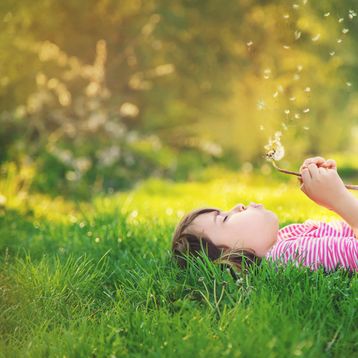 Niña jugando con diente de león